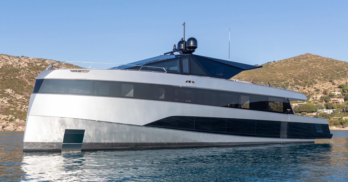 Wally wallywhy200 shown from water level looking towards port bow and side profile. yacht is stationary in calm waters with land in background on calm day