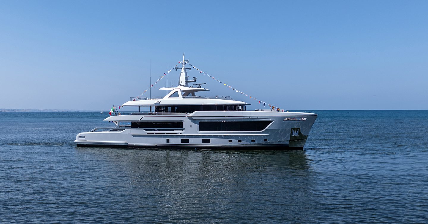 CDM explorer yacht BABBO long shot taken mid aerial over water looking towards starboard side profile of the yacht on a calm sea and a clear bright sky