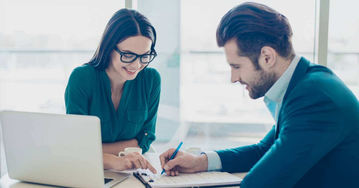 Broker and owner reviewing paperwork with a laptop 
