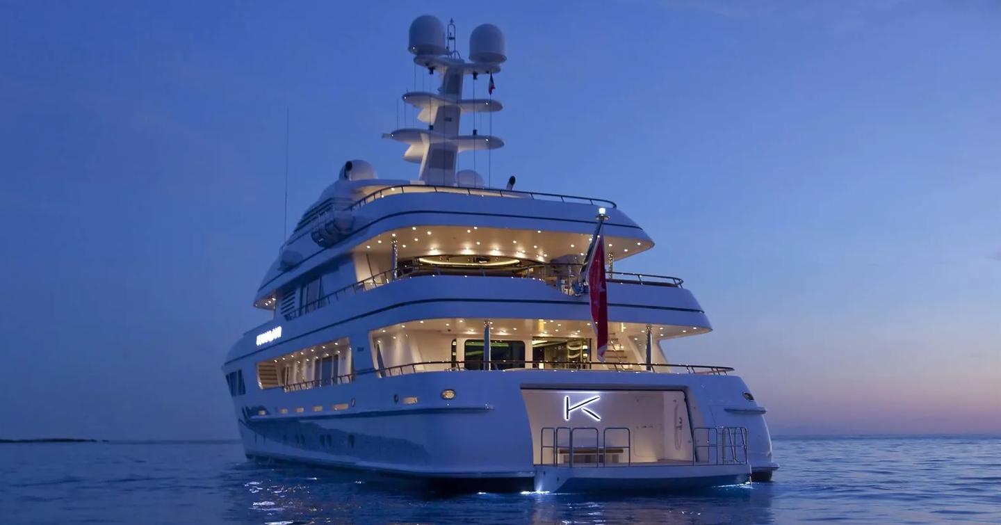 Feadship yacht KAHALANI shown from water level towards stern, at night as the transom door is open and lights seen from the interior