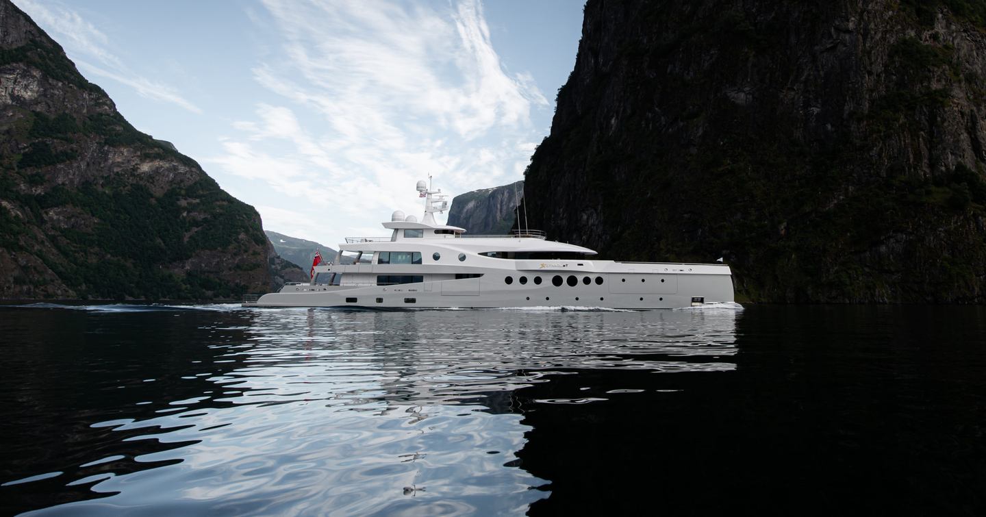 Side view of Amels Limited Editions 206 STARDUST underway, surrounded by sea and towering rock formations