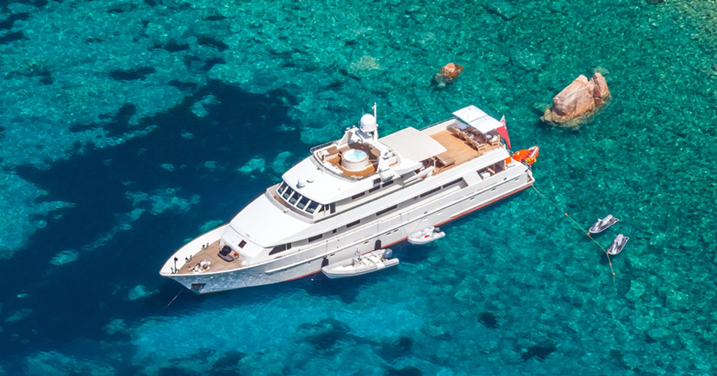 Yacht at anchor in shallow rocky waters 