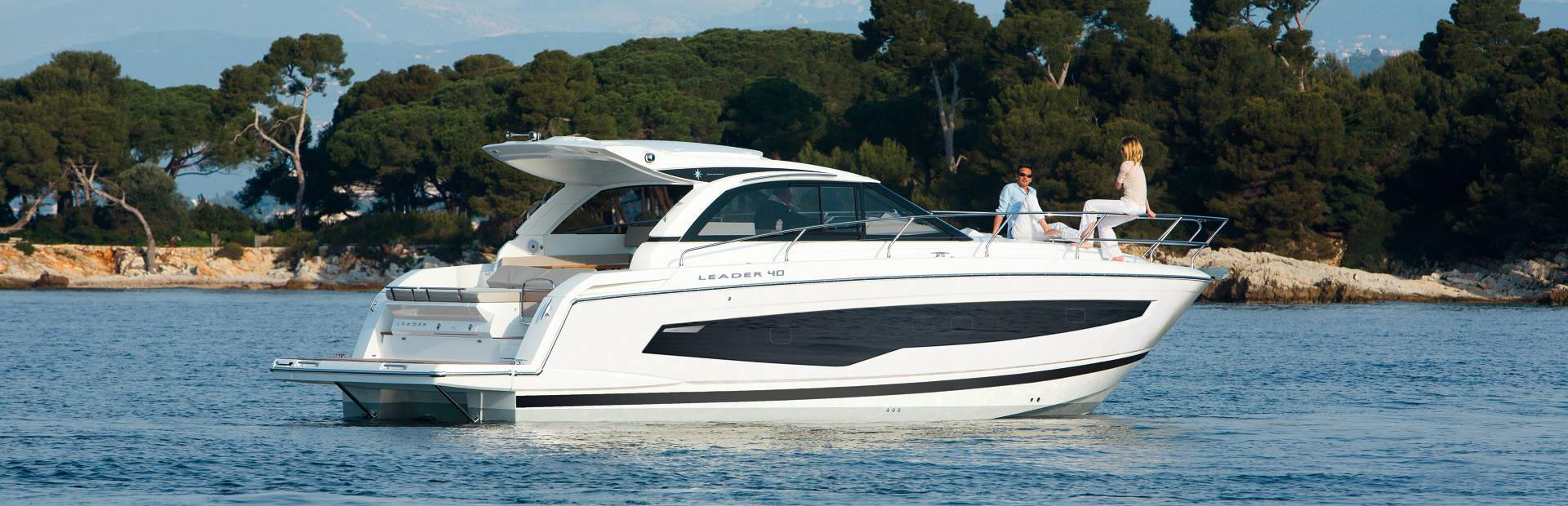 Jeanneau boat at anchor on water with couple talking onboard