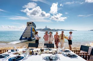 hospitality crew with guests at beach picnic superyacht background