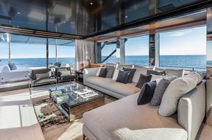 rendering of large L-shaped, grey sofa, coffee table and wall of windows in the main salon of the Argo 90 yacht