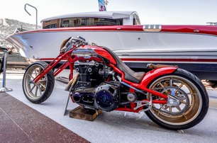 red motorbike in front of yacht with red trim at Monaco Yacht Show