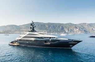 ISA superyacht RESILIENCE for sale at 2024 Monaco Yacht Show shown underway but not making way, in calm sea with land in background, starboard side profile