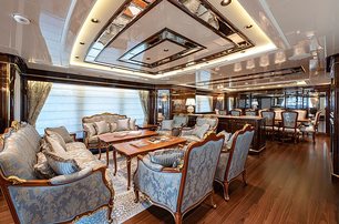 Interior lounge on Sanlorenzo Lady Lena superyacht, coffee table and seating in foreground with formal dining table in background