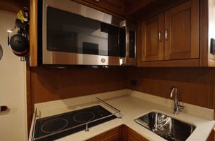 Fleming 85 crew galley with cooktop, microwave and storage cabinetry
