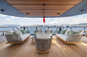 Mangusta Oceano 39 exterior salon with freestanding furniture looking from the yachts interior out to sea, land in background