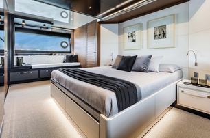 rendering of a large bed with white linen and a black runner, white wall panels and a white carpet in the master suite on board the Argo 90 yacht