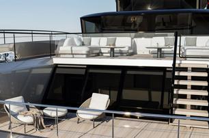 Sunreef Ultima 111 aft deck shown with freestanding furniture and stairway to upper deck level with more seating