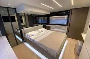 Sessa Marine F60 Flybridge cabin in muted tones, with ceiling light and under bed illumination, ecru carpet, large window in background