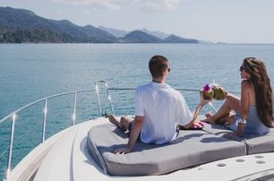 young couple with drinks on bow of small yacht