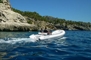 Williams SportJet 520 yacht tender running shot taken water level over starboard aft and along side profile, single person onboard driving, mountainous land in background