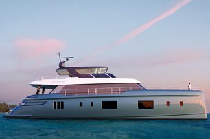 100 Sunreef Power shot from water level towards full starboard profile, bright day with streaks of cloud in sky, calm sea; person in white shirt standing on bow 