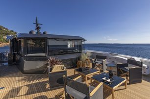 Arcadia A96 motor yacht upper deck as sun starts to set, free standing furniture show plenty of seating, smooth sea in background, shot taken from back of aft deck