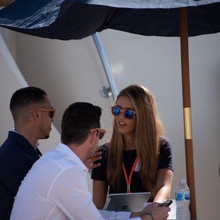 three people under parasol talking at yacht show