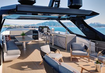 Sunseeker 94 Yacht sky deck lounging area and salon with bar, free standing furniture, sun creating shadow, looking forward from port quarter 