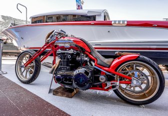 red motorbike in front of yacht with red trim at Monaco Yacht Show