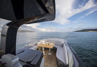 Sacs Tecnorib Strider 13 shot taken from onboard looking at the bow that has table set for dining, calm sea, bright sky approaching twilight, land to both sides but open view dead ahead