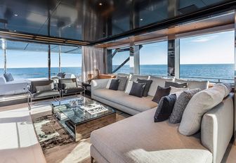 rendering of large L-shaped, grey sofa, coffee table and wall of windows in the main salon of the Argo 90 yacht