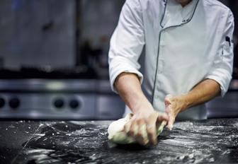 Superyacht chef kneading dough for fresh bread onboard