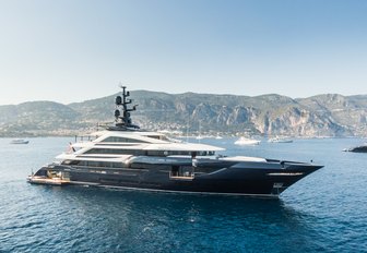 ISA superyacht RESILIENCE for sale at 2024 Monaco Yacht Show shown underway but not making way, in calm sea with land in background, starboard side profile