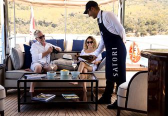 yacht crew steward pouring champagne for guests