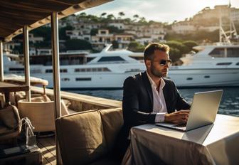 yacht charter manager on laptop in marina