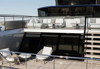 Sunreef Ultima 111 aft deck shown with freestanding furniture and stairway to upper deck level with more seating