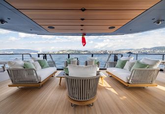 Mangusta Oceano 39 exterior salon with freestanding furniture looking from the yachts interior out to sea, land in background