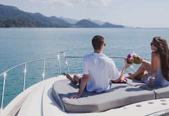 young couple with drinks on bow of small yacht