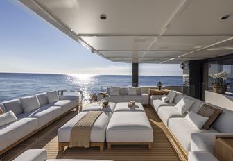 Arcadia A96 motor yacht aft deck exterior salon as sun is setting, ample sofas, looks very calm and relaxing