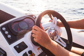 Williams SportJet 520 yacht tender hem console, person with hand on wheel and throttle, viewed from port side towards starboard positioned elm 