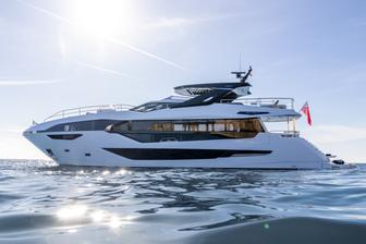 Sunseeker 100 Yacht still in calm waters, shot taken from water level towards port side profile, bright sun blue sky