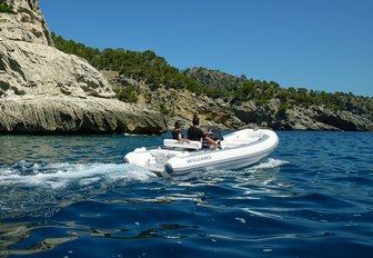 Williams SportJet 520 yacht tender running shot taken water level over starboard aft and along side profile, single person onboard driving, mountainous land in background