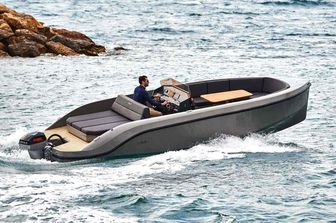 Rand Boats Play 24 running shot mid aerial view over starboard aft and along side profile, one person onboard, rocky background, moderate sea