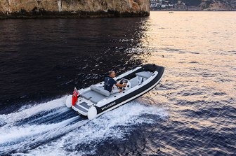 Williams SportJet 520 yacht tender running shot mid aerial taken over starboard aft and along side profile, single person onboard driving , red ensign, mountainous land in background