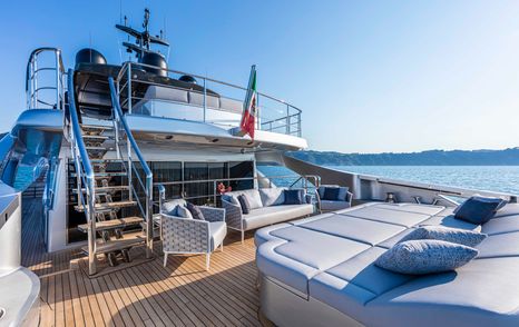 Exterior sunbathing area onboard Pershing 140 'Touch Me', large sunpads to starboard with rattan seating facing, surrounded by sea and land in distance