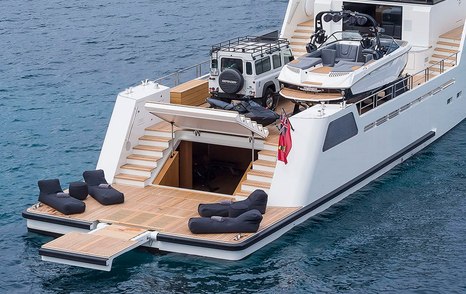 Aft of YXT 24 Evolution, with tender and four by four on main deck, with four sunloungers on swim platform