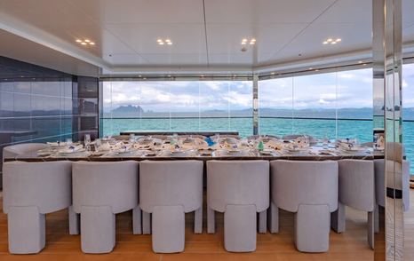 Formal dining set up onboard superyacht WANDERLUST. Total of 14 seats sat around table with extensive glazing in the background.