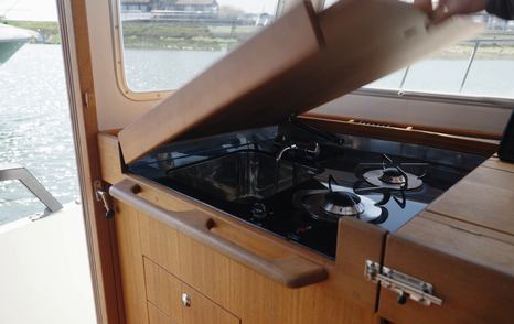 Compact gas hob beneath a hinged wooden worktop in the Botnia Targa 32 galley, used during the Prop Gear afternoon-tea challenge.