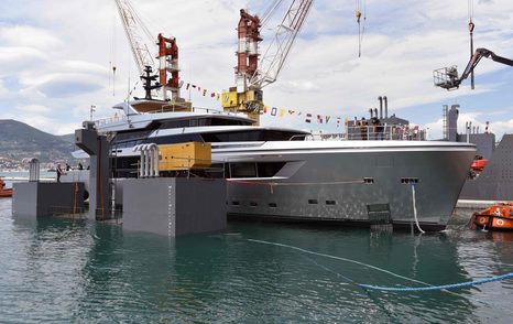 Side view of Sanlorenzo 44Alloy H1 surrounded by cranes and sea, with mountain range in backdrop