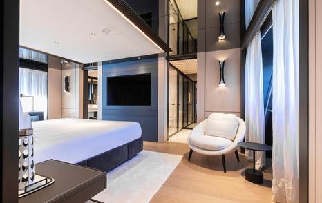 Superyacht Andala master cabin with mounted TV and white chair 