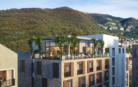 Al fresco dining at Boka Place, Porto Montenegro. Visitors sat at tables on a rooftop layout, with mountains in background.