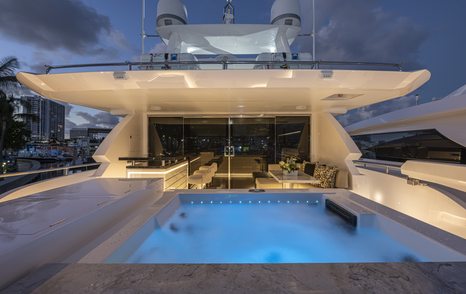 Overview of the aft bridge deck onboard ISSIMO, on deck Jacuzzi to starboard with interiors visible through glass doors.