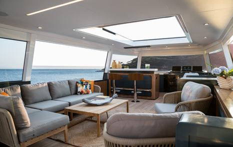 Interiors on the flybridge of the Sirena 78. Grey seating arranged around central coffee table and helm station located forward. 