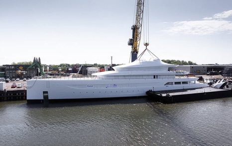 Superyacht Feadship 828 docked outside shipyard with crane attached to upper decks 