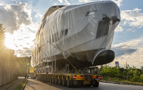 Frontal view of Numarine 26XP bow sat on a trailer, covered in protective wrapping surrounded by road and green foliage